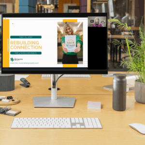 A computer on an office desk displays the welcome screen for The Restoration Project's Rebuilding Connection Course
