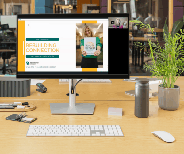 A computer on an office desk displays the welcome screen for The Restoration Project's Rebuilding Connection Course