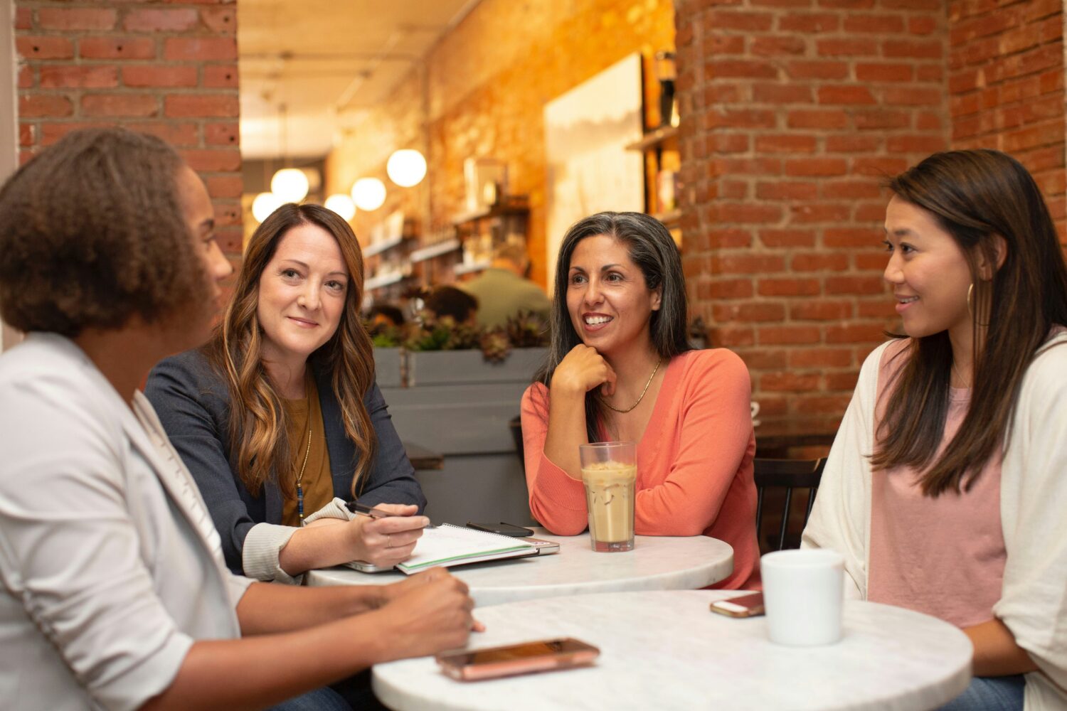 Group of Women Seated Around a Table Talking with Each Other.