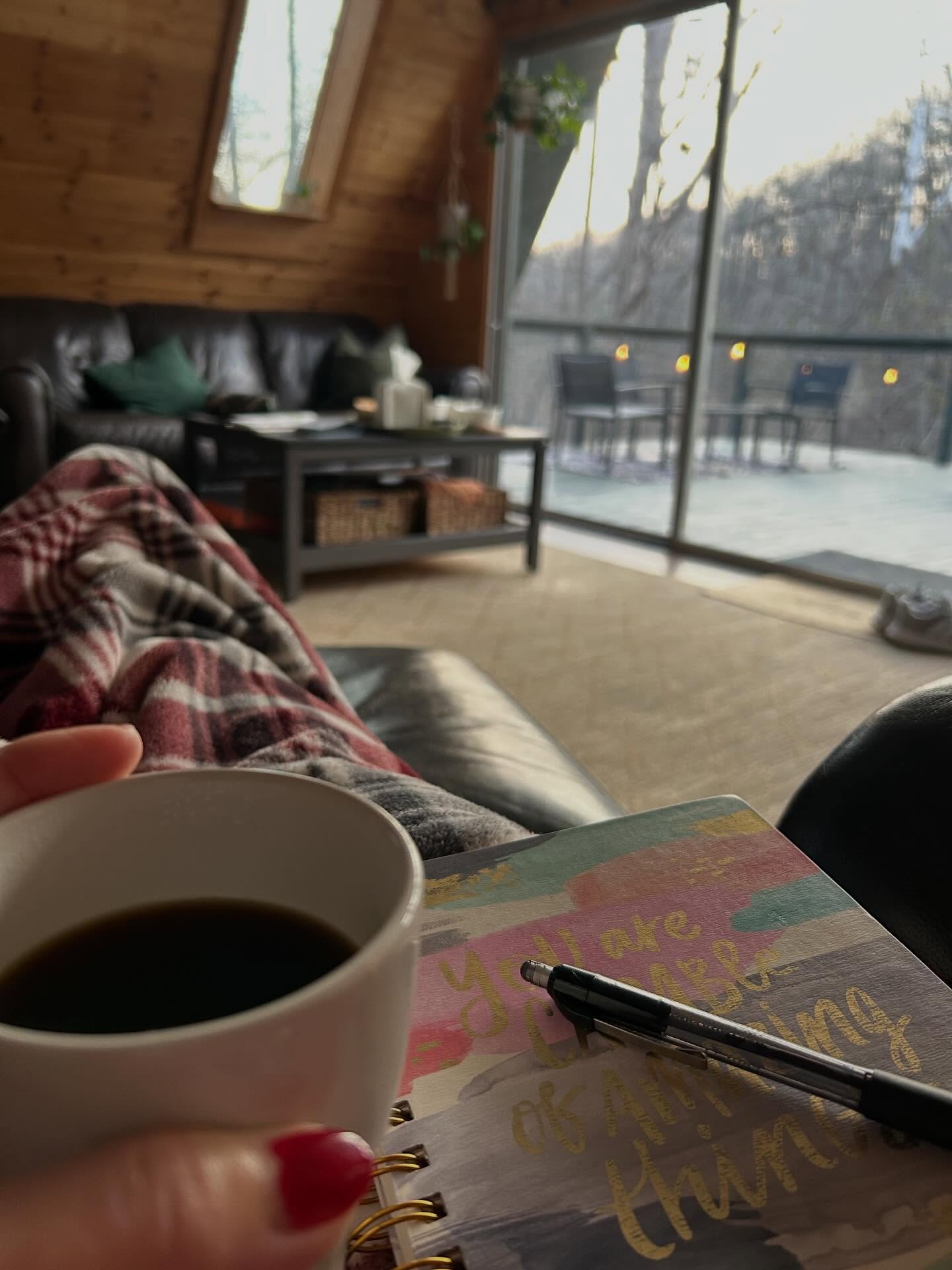 A woman with her feet up, a journal on her lap and coffee in hand